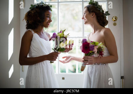 Braut und Brautjungfern mit Blumenstrauß zu Hause stehend Stockfoto