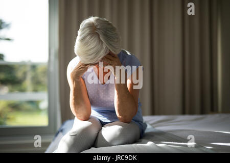 Portrait von angespannten Senior Frau sitzt auf dem Bett im Schlafzimmer zu Hause Stockfoto