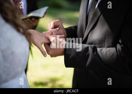 Den mittleren Abschnitt der Bräutigam das Engagement Ring in der Frau Finger Stockfoto