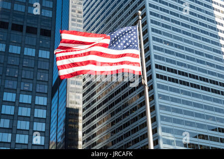 Amerikanische Flagge im Wind mit Wolkenkratzern im Hintergrund Stockfoto