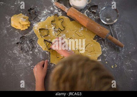 Zugeschnittenes Bild der Boy, Formen von Cookie Cutter auf den Küchentisch Stockfoto