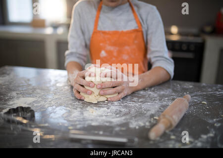 Den mittleren Abschnitt der kleinen Mädchen, dass Teig in ihre Hand auf die Arbeitsplatte in der Küche Stockfoto