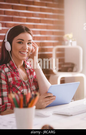 Portrait von lächelnden Executive hören Musik auf digitalen Tablette im Büro Stockfoto