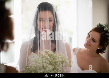 Portrait von lächelnden Braut mit Blumenstrauß zu Hause Stockfoto