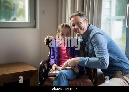 Lächelnd Vater und Tochter ein Buch zu Hause lesen Stockfoto