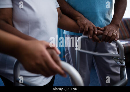 Mittelteil der Freund der Frau zu Fuß mit Walker in den Ruhestand home Stockfoto