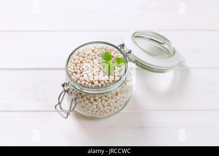 Jar von rohem Holz weiße Bohnen auf weißem Hintergrund Stockfoto