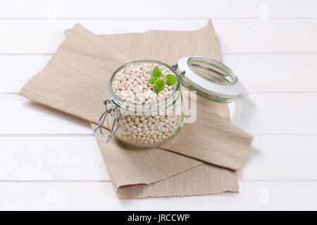 Jar von weißen Bohnen auf beige Unterlage Stockfoto