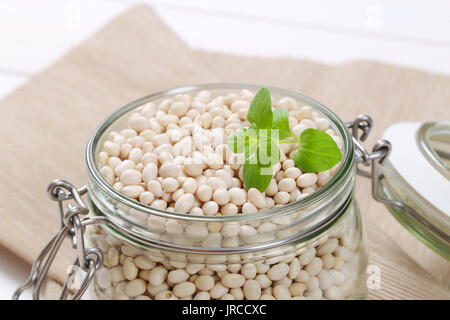 Jar von weißen Bohnen auf beige Unterlage - Nahaufnahme Stockfoto