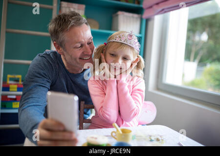 Lächelnd Vater einen selfie seiner Tochter tragen als Märchen gekleidet Stockfoto