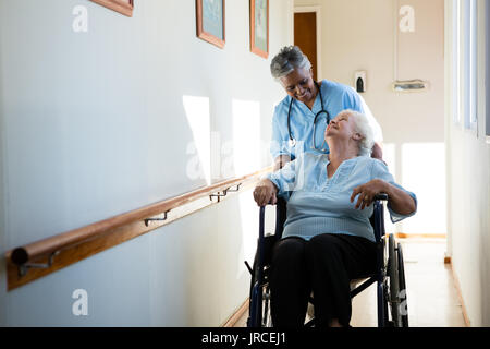 Krankenschwester sprechen und gleichzeitig den Patienten im Rollstuhl am Pflegeheim sitzen Stockfoto