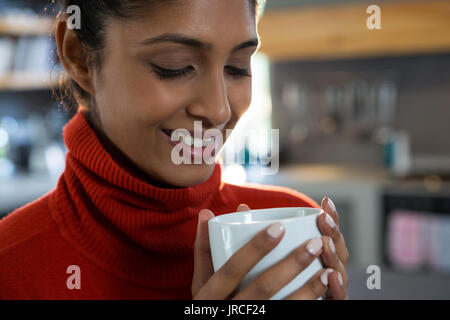 Lächelnden jungen Frau Kaffee in der Küche zu Hause. Stockfoto