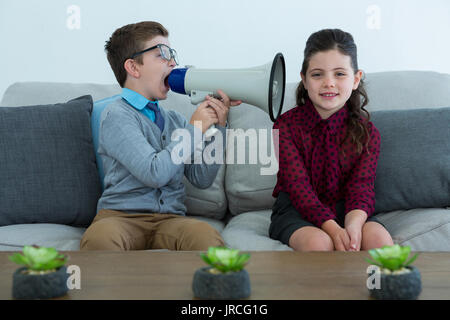 Geschäftsmann über Megaphon in weiblichen Kollegen Ohr schreien im Büro Stockfoto
