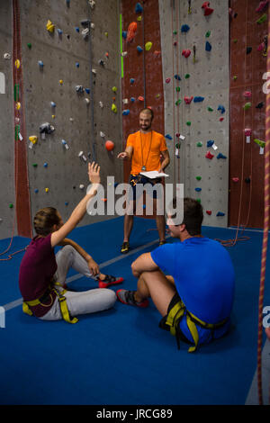 Männliche trainer Interaktion mit Athleten sitzen auf dem Boden im Fitnessstudio Stockfoto