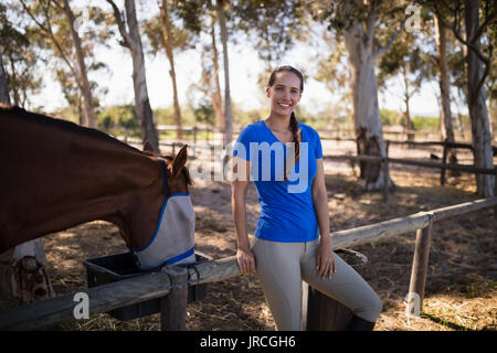 Porträt der Frau, die mit dem Pferd auf dem Feld im Fahrerlager Stockfoto