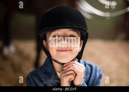 Porträt der lächelnde Mädchen Befestigung Helm beim Stehen in der stabil Stockfoto