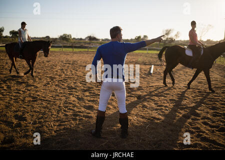 Männliche Trainer jungen Frauen in Reiten in der Scheune Stockfoto