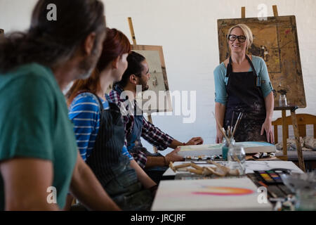 Erwachsene Schüler betrachten lächelnd weibliche Lehrer stehen in der Kunst Klasse Stockfoto