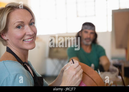 Portrait von Frau dekorieren Tontopf mit Schüler im Hintergrund sitzen Stockfoto