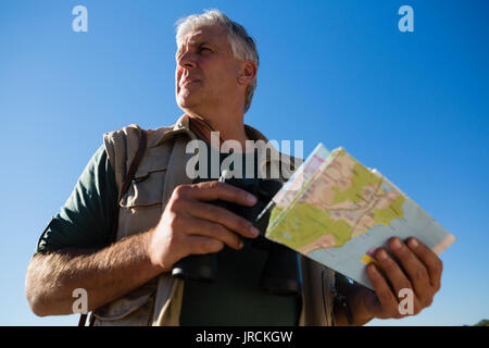 Low Angle View der Mann hält Karte gegen den blauen Himmel Stockfoto