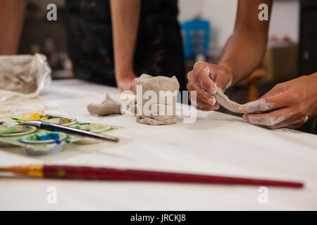 Den mittleren Abschnitt des Menschen Unterstützung der Frau in molding Clay während des Zeichnens Klasse Stockfoto