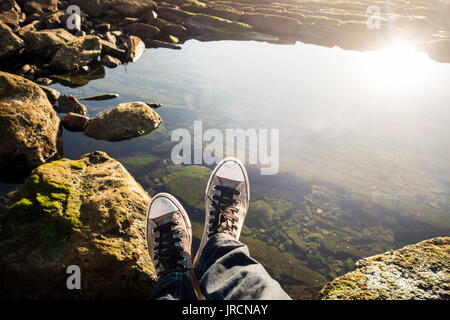 Niedrige Abschnitt einer Person sitzen auf den Felsen vor Wasser Stockfoto