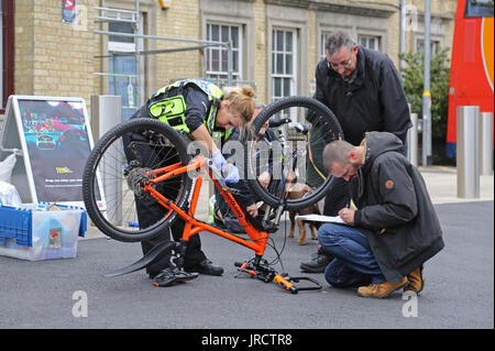 Ein Fahrrad Registrierung Veranstaltung in Cambridge, Großbritannien. Eine Polizistin Sicherheit ist ein Rad, während Details von einem Kollegen aufgezeichnet werden. Stockfoto