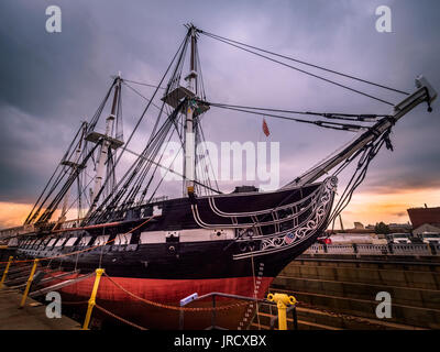 USS Constitution angedockt an Boston Harbor Hotel in Charlestown, Massachusetts, USA mit wunderschönen Sonnenuntergang im Hintergrund an einem bewölkten Tag. Stockfoto