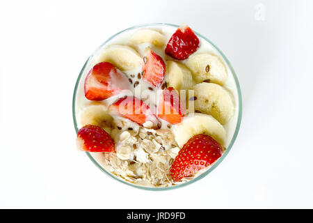 Weiß hausgemachte Joghurt mit Haferflocken Erdbeere und Banane und Leinsamen in ein Becherglas auf einem weißen Hintergrund. Ansicht von oben Stockfoto