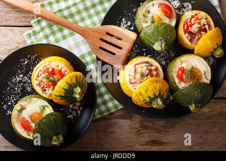 Leckere runde Zucchini gebacken mit Bulgur und Fleisch, sowie ein Ei mit Tomaten close-up auf einem Teller. Horizontale Ansicht von oben Stockfoto