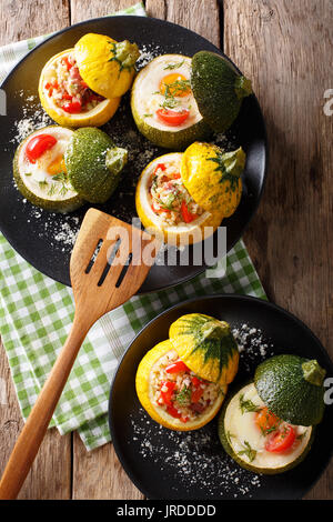 Leckere runde Zucchini gebacken mit Bulgur und Fleisch, sowie ein Ei mit Tomaten close-up auf einem Teller. Vertikale Ansicht von oben Stockfoto