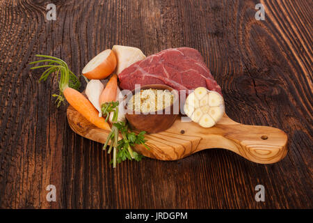 Frische Suppe Zutaten auf Holz- rustikalen Tisch. Frisches Gemüse und rohes Fleisch auf Schneidebrett. Stockfoto