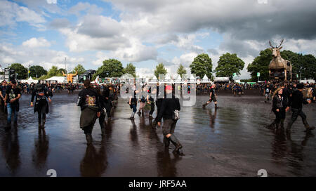 Wacken, Deutschland. 4. August 2017. Festival-Besucher geht durch den Schlamm auf dem Gelände der Wacken Open Air-Festivals in Wacken, Deutschland, 4. August 2017. Wacken Open Air findet zwischen 03 und 5. August 2017. Foto: Christophe Gateau/Dpa/Alamy Live News Stockfoto