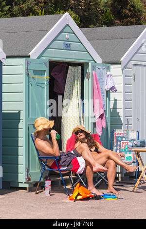 Bournemouth, Dorset, Großbritannien. 5 Aug, 2017. UK Wetter: schön warmen, sonnigen Nachmittag, als Besucher der seaside Kopf den Sonnenschein an Alum Chine Beach zu machen. Paar entspannende außerhalb Umkleidekabinen am Strand in der Sonne. Credit: Carolyn Jenkins/Alamy leben Nachrichten Stockfoto