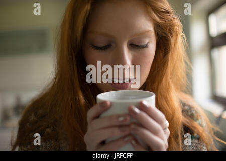 Nahaufnahme von Frau Kaffee im Stehen durch Fenster Stockfoto