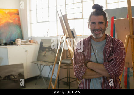 Portrait von lächelnden reifen Künstler mit gekreuzten Armen stehen in art studio Stockfoto
