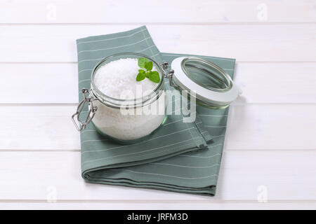 Jar von grobkörnigem Meersalz auf grauer Unterlage Stockfoto