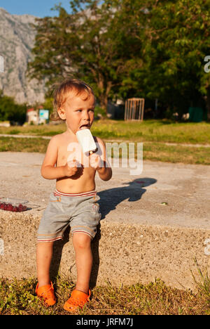 Der kleine Junge isst Eis in Sonnenuntergang leuchtet Stockfoto