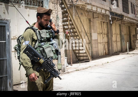 Israelischer Soldat bewacht ein ehemaliger bustiling Hebron market Street jetzt für die Palästinenser aufgrund einer landnahme von 850 israelische Siedler geschlossen in der Nähe Stockfoto