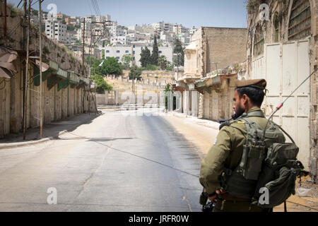 Israelischer Soldat bewacht ein ehemaliger bustiling Hebron market Street jetzt für die Palästinenser aufgrund einer landnahme von 850 israelische Siedler geschlossen in der Nähe Stockfoto