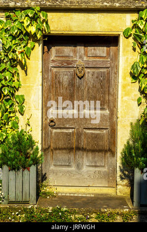 stilvolle Eintritt in ein Wohnhaus, eine interessante Fassade der alten Steinmauer, alte Holztür, typische alte englische Gebäude, Architektur Stockfoto
