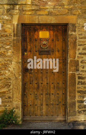 stilvolle Eintritt in ein Wohnhaus, eine interessante Fassade der alten Steinmauer, alte Holztür, typische alte englische Gebäude, Architektur Stockfoto