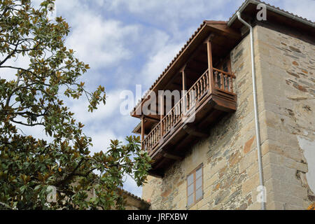 Ein poliertes Holz Balkon eines Hauses aus Stein, mit einem grünen Baum und ein blauer Himmel Stockfoto