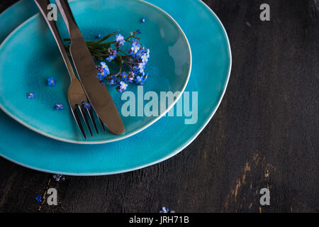 Sommer Blumen Tischdekoration mit leuchtend blauen Vergissmeinnicht Blumen auf Holztisch Stockfoto