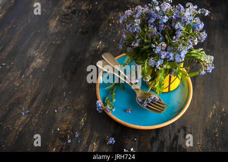 Sommer Blumen Tischdekoration mit leuchtend blauen Vergissmeinnicht Blumen auf Holztisch Stockfoto