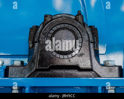 Schwarze Kugel Lagergehäuse auf eine blaue Maschine. Ende der Antriebswelle sichtbar. Schmiernippel auf der Oberseite des Gehäuses. Stockfoto