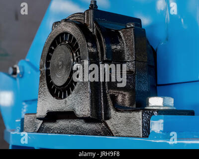 Schwarze Kugel Lagergehäuse auf eine blaue Maschine. Ende der Antriebswelle sichtbar. Schmiernippel auf der Oberseite des Gehäuses. Stockfoto