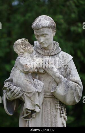 Statue von Kind sitzen auf Mönche arm, Konzept der Liebe das Christentum Gott Spiritualität grüner Baum im Hintergrund mit Kopie Raum Stockfoto