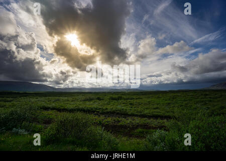 Island - Sonne bricht durch die Wolken über dem endlosen grünen Bereich Stockfoto