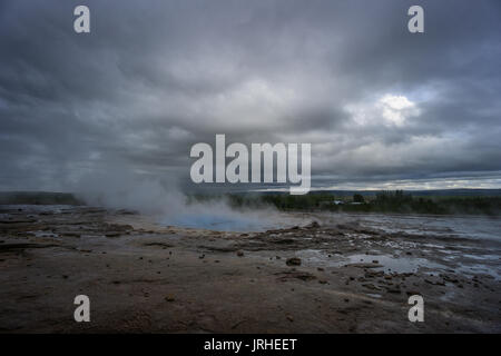 Island - Türkis heißen kochendes Wasser, vor Ausbruch des Geysir Strokkur mit Bäumen Stockfoto
